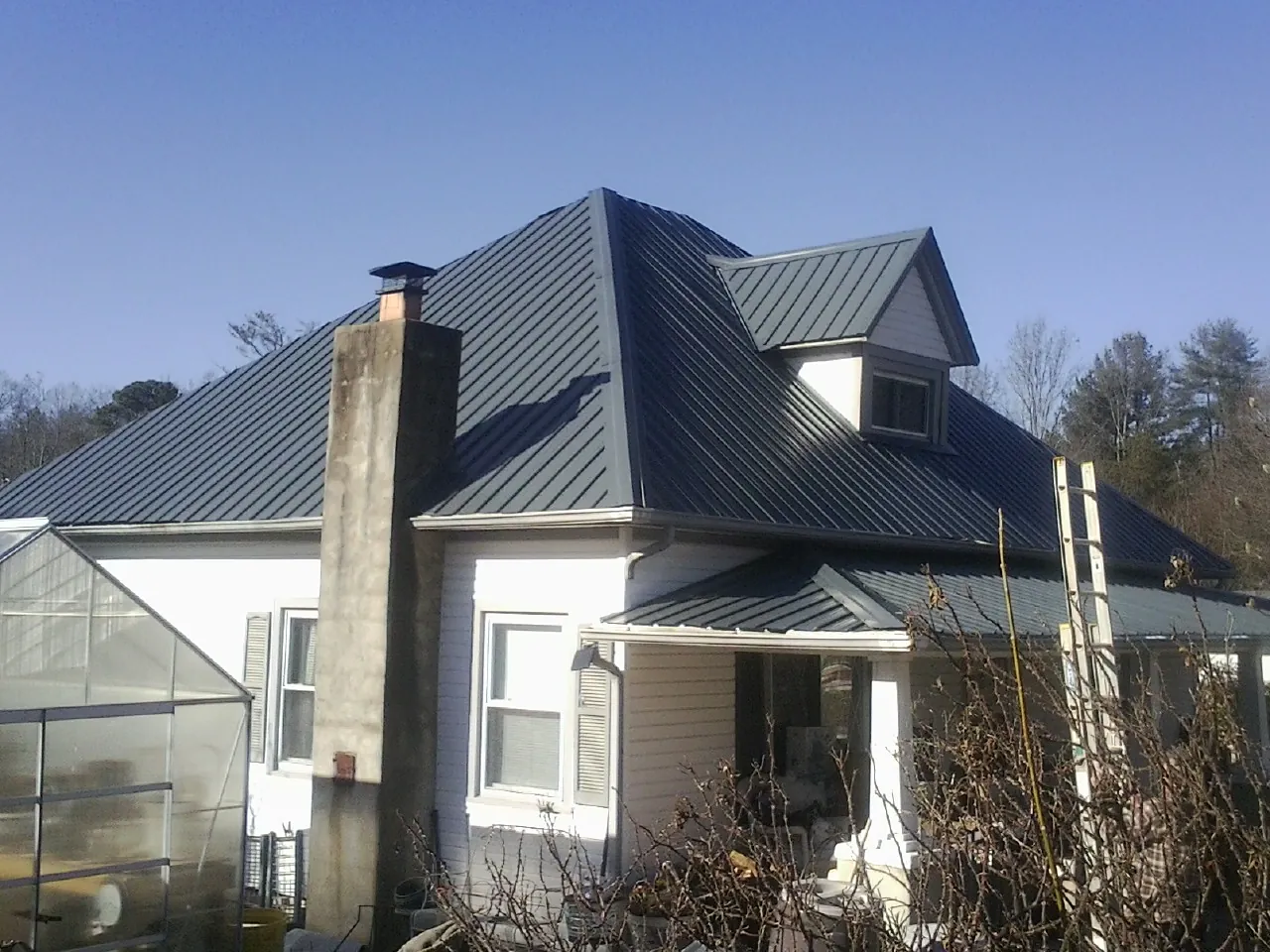 Dark blue standing seam metal roof on a white farmhouse with dormer — Slate & Tile Roof Repair by Roofing Brothers in Palos Verdes Peninsula