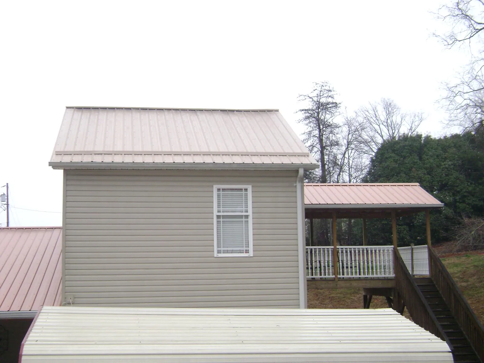 Tan metal roofs on a two story addition and attached porch, from a Roof Replacement job in Palos Verdes Peninsula