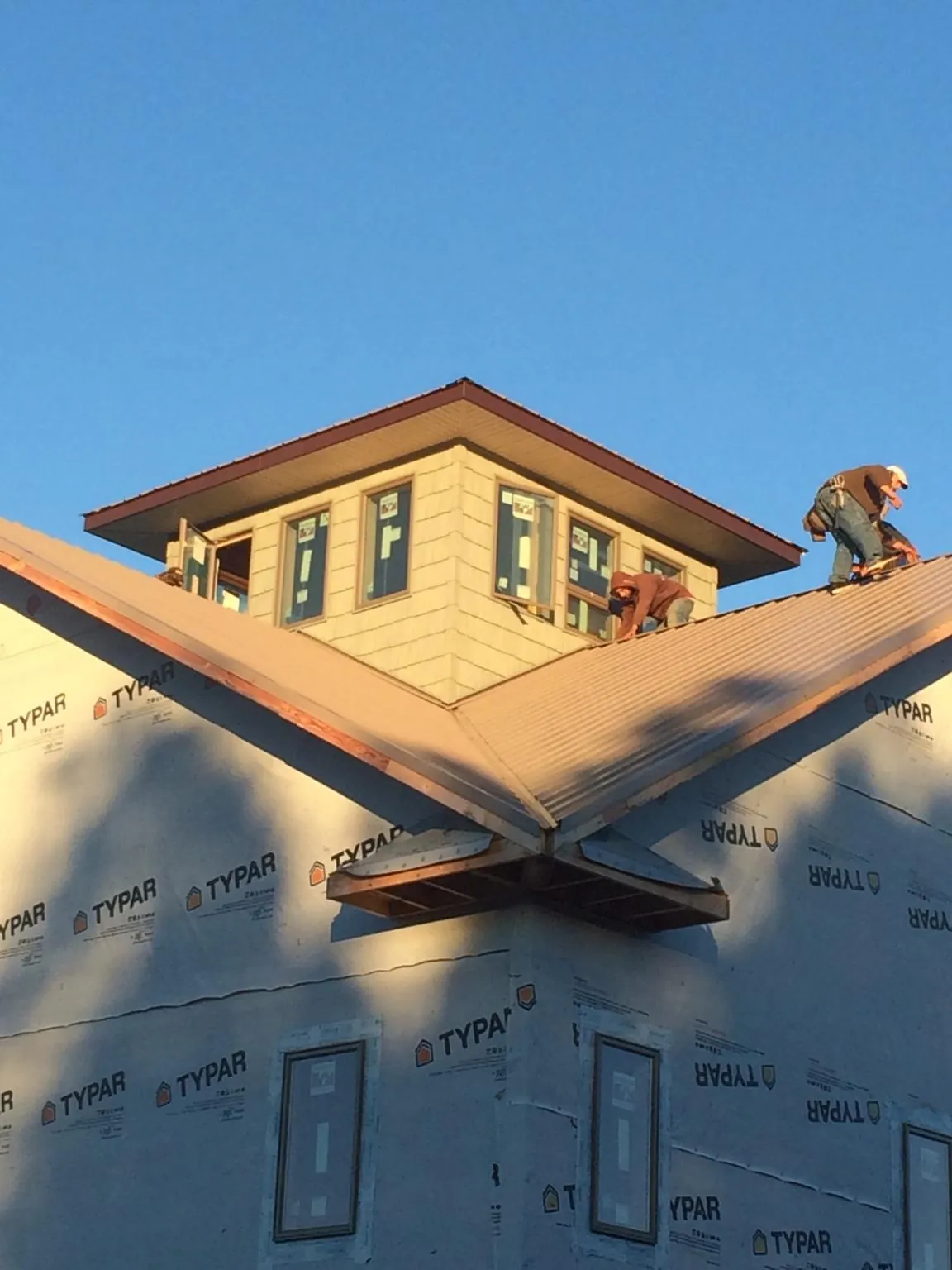 Roofers working around a rooftop cupola on a new metal roof at sunset — Roof Waterproofing in Palos Verdes Peninsula by Roofing Brothers